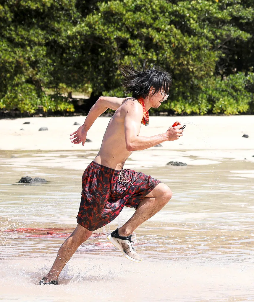 Myles, wearing only long baggy shorts, runs along a beach in Samoa for Australian Survivor.