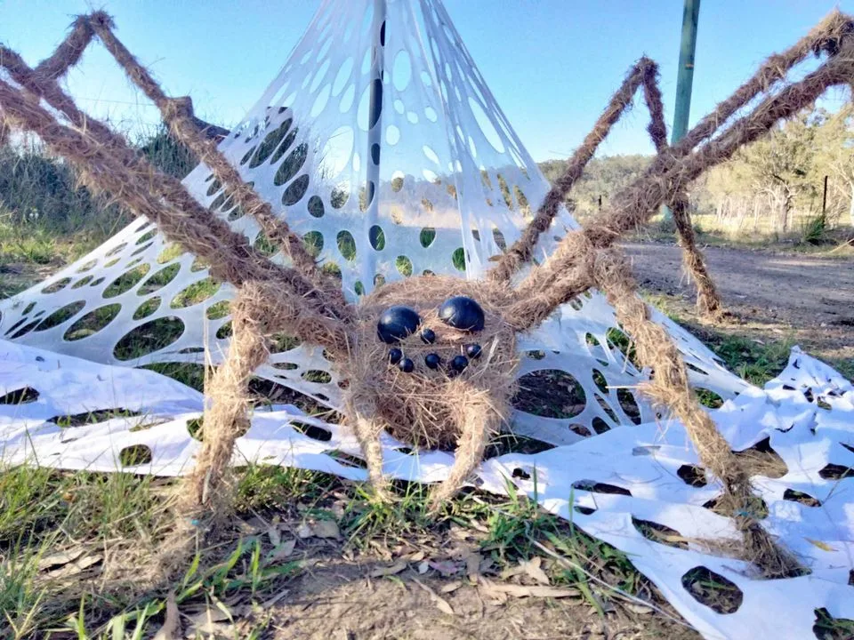 Scarecrow as a giant huntsman spider sitting in a giant web