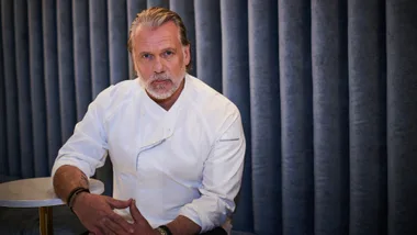 A man wearing a white shirt looks sternly into the camera.