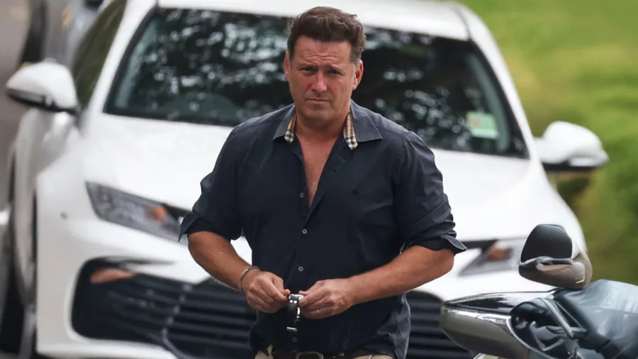 An image of a middle aged man in front of a white car.