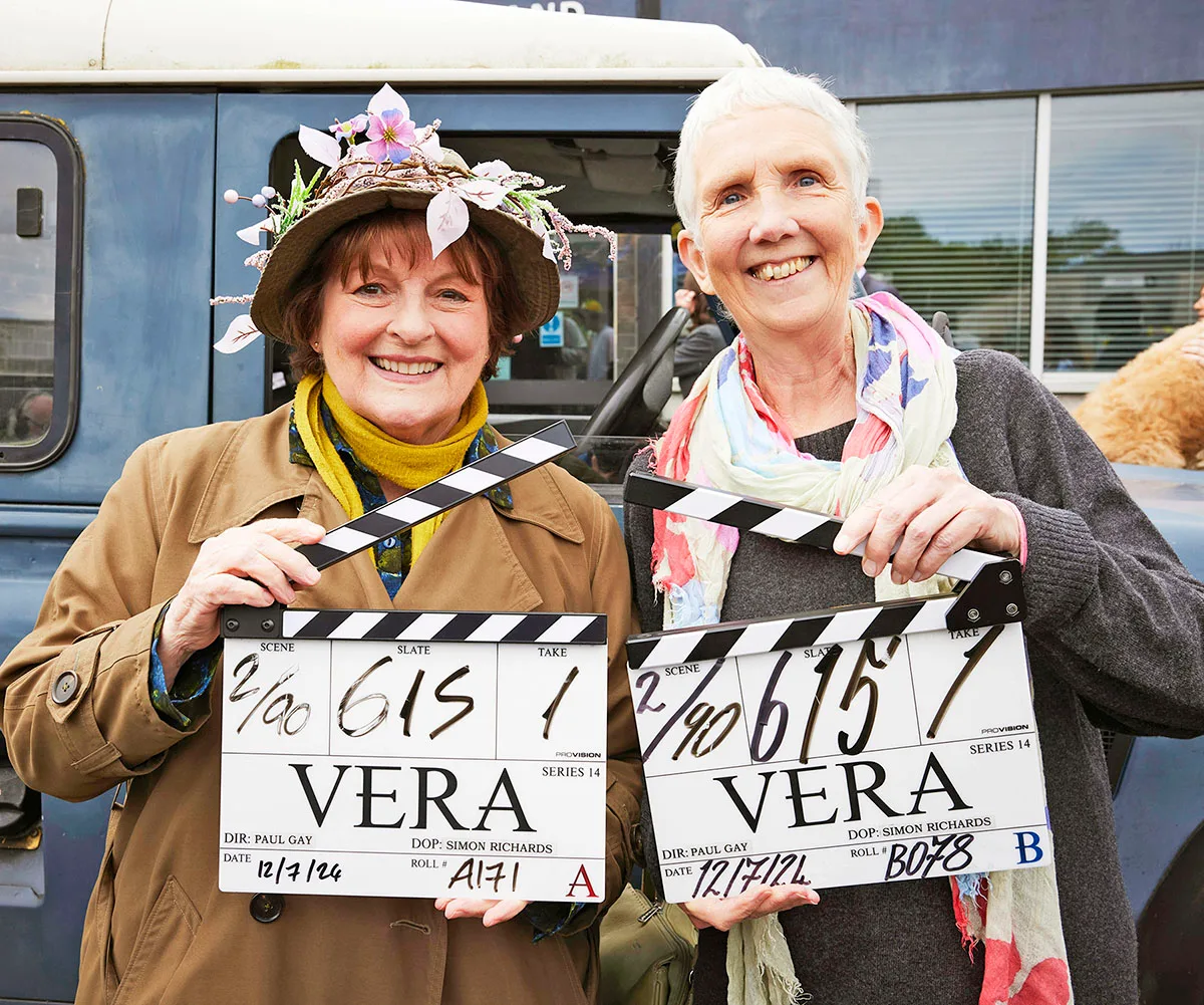 Brenda Blethyn and Anne Cleaves on set of Vera each holding a film slate for a scene with big grins on their face
