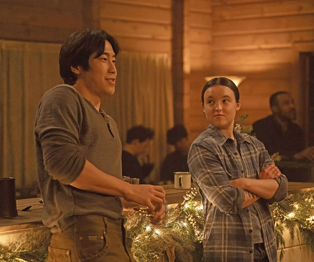 Newcomer Jesse stands next to Ellie at a barn dance as he smiles and she looks at him suspiciously