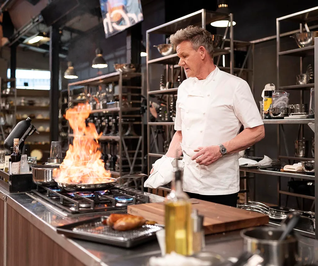 Gordon Ramsay in the MasterChef kitchen looking at a pan in flames on the stovetop