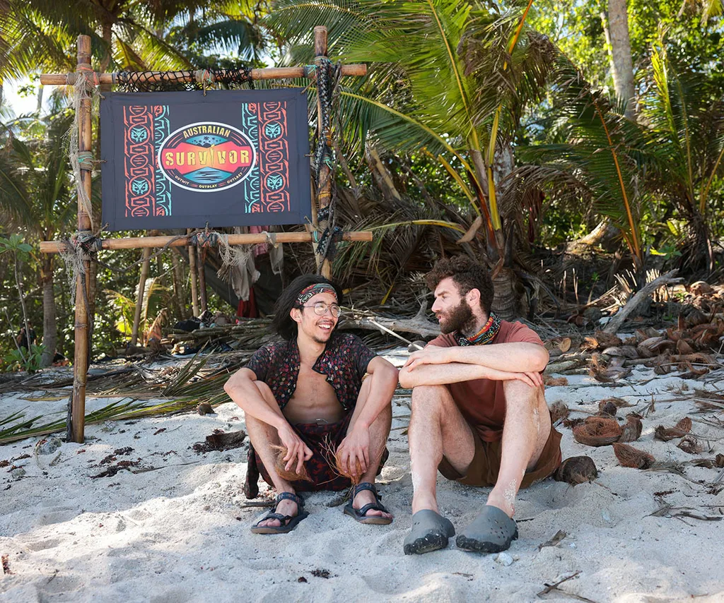 Myles and AJ, sitting on the beach in Samoa, looking at each other.
