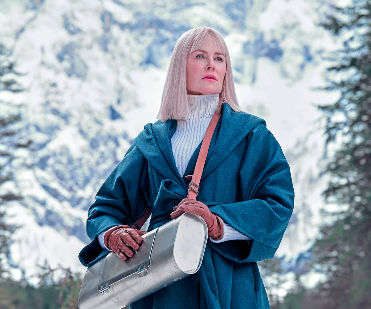 Nicole Kidman in Nine Perfect Strangers dressed in a blue trench coat, short blonde bob, white turtle neck, red gloves and a silver container swung across her body