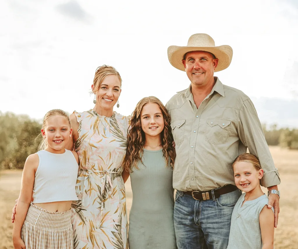 Farmer Brad and Stacie pose with their children in a field.