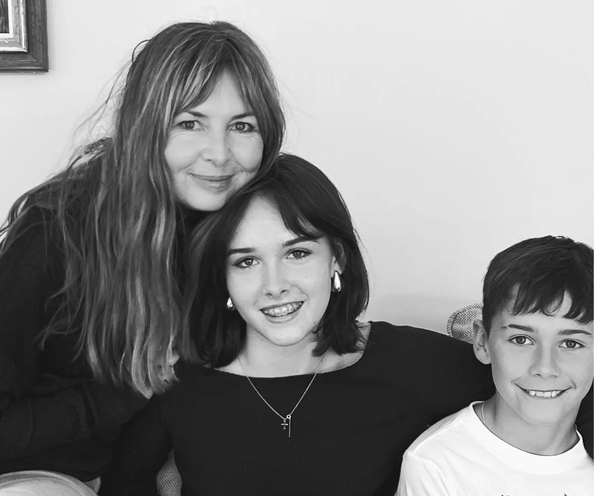 A black and white photo of two women and a young boy, smiling.