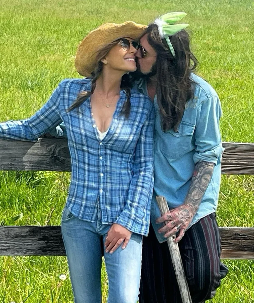 A couple stand at a fence nuzzling each other