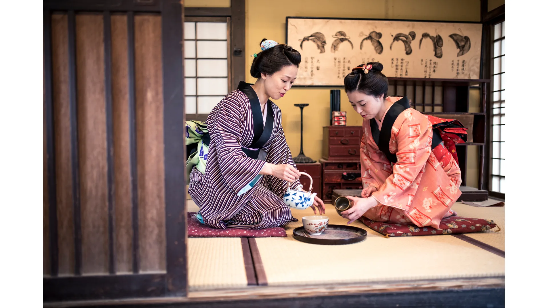 Two geisha perform a traditional Japanese tea ceremony in a teahouse.
