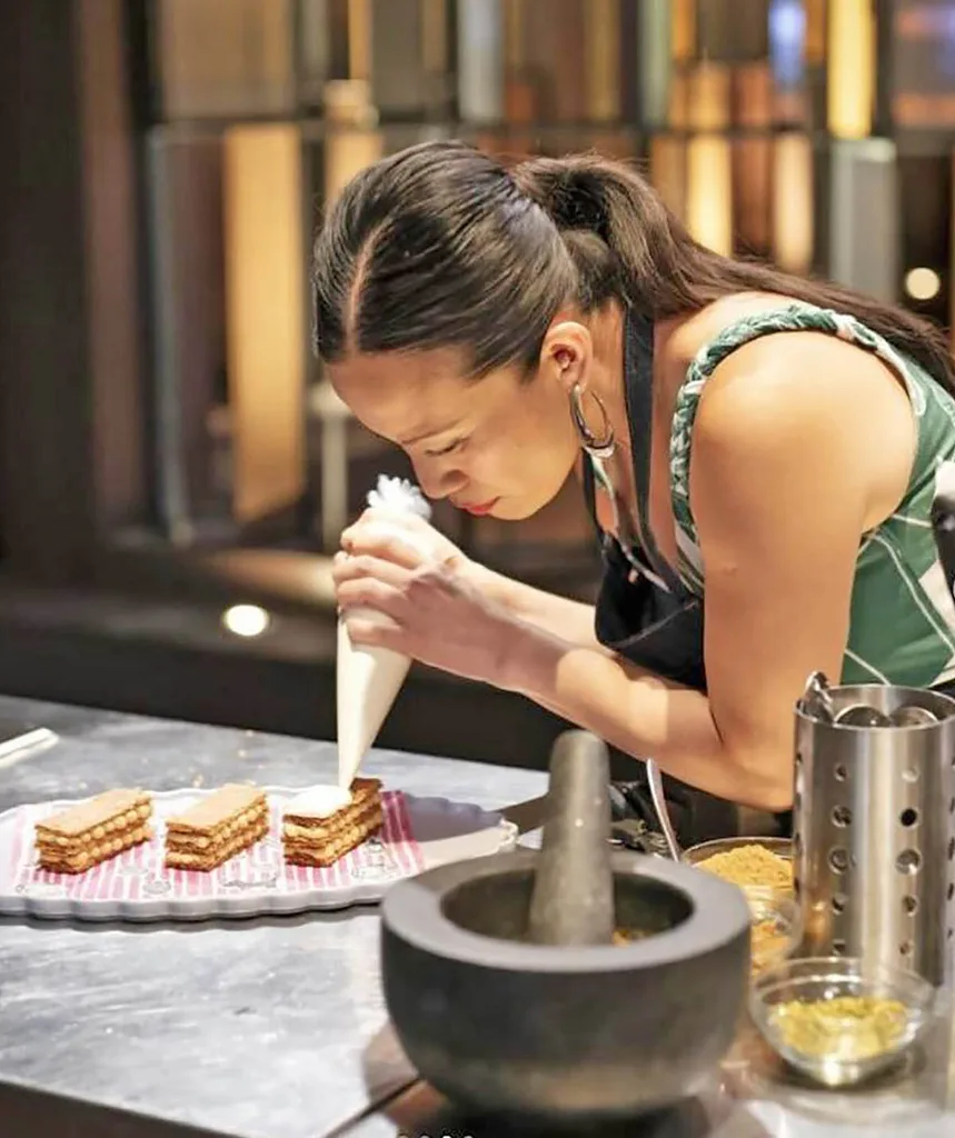 Poh is pictured in the MasterChef kitchen when she was a contestant and she is piping out cream onto a delicious looking dessert with a look of intense focus on her face