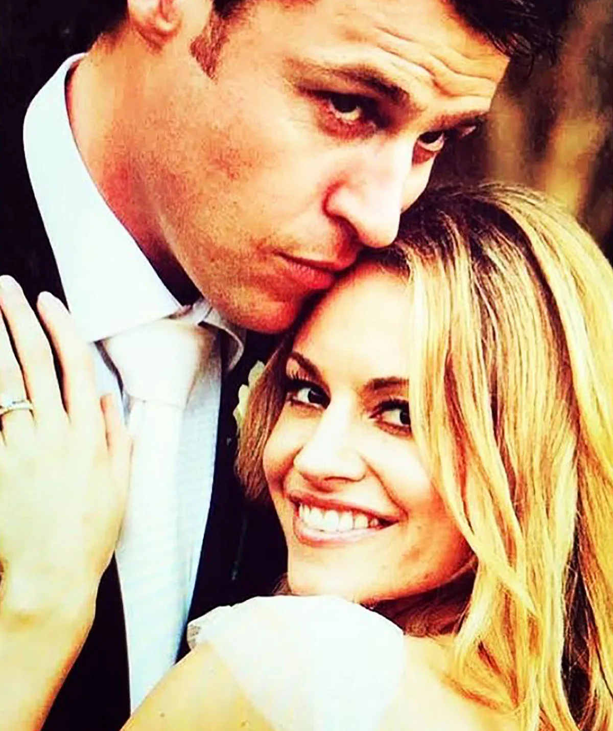 Rodger wears a suit and kisses his wife Renae's forehead as she smiles on their wedding day