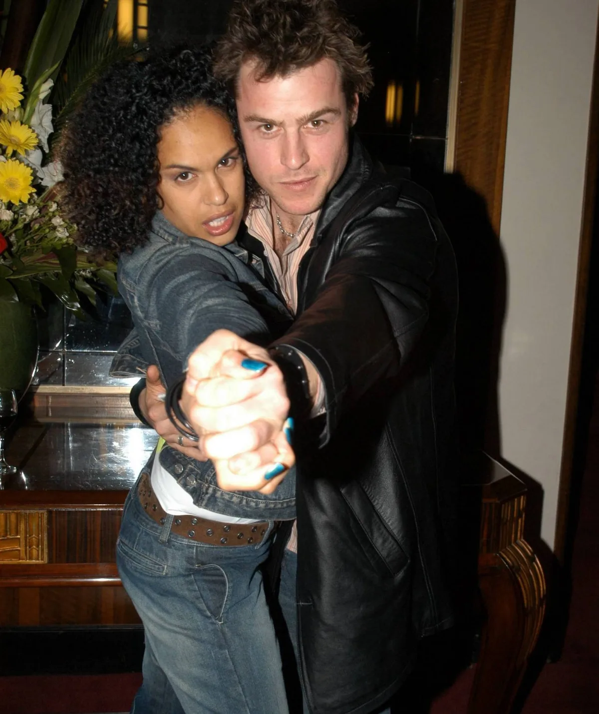 A man and woman pose as though they are dancing with their arms outstretched.