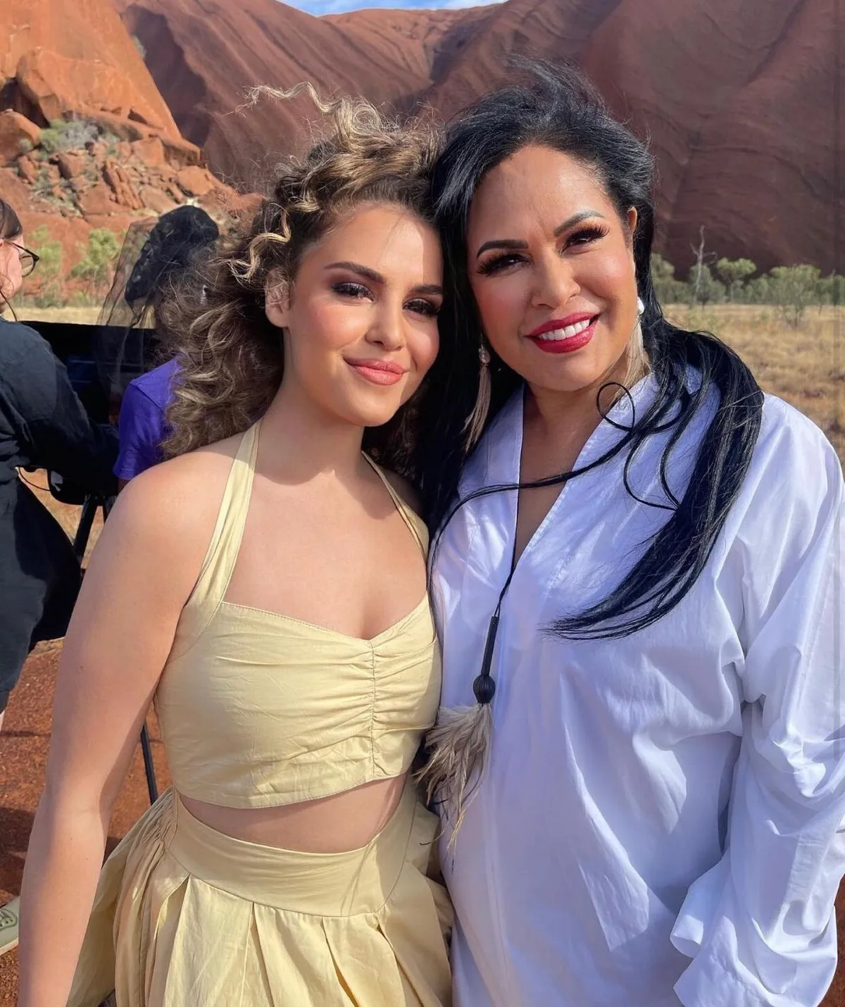 Two woman smile at the camera in front of Uluru.