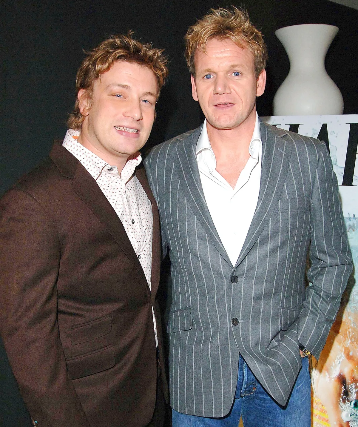 Two white men look at the camera, they are both wearing suits and white shirts.