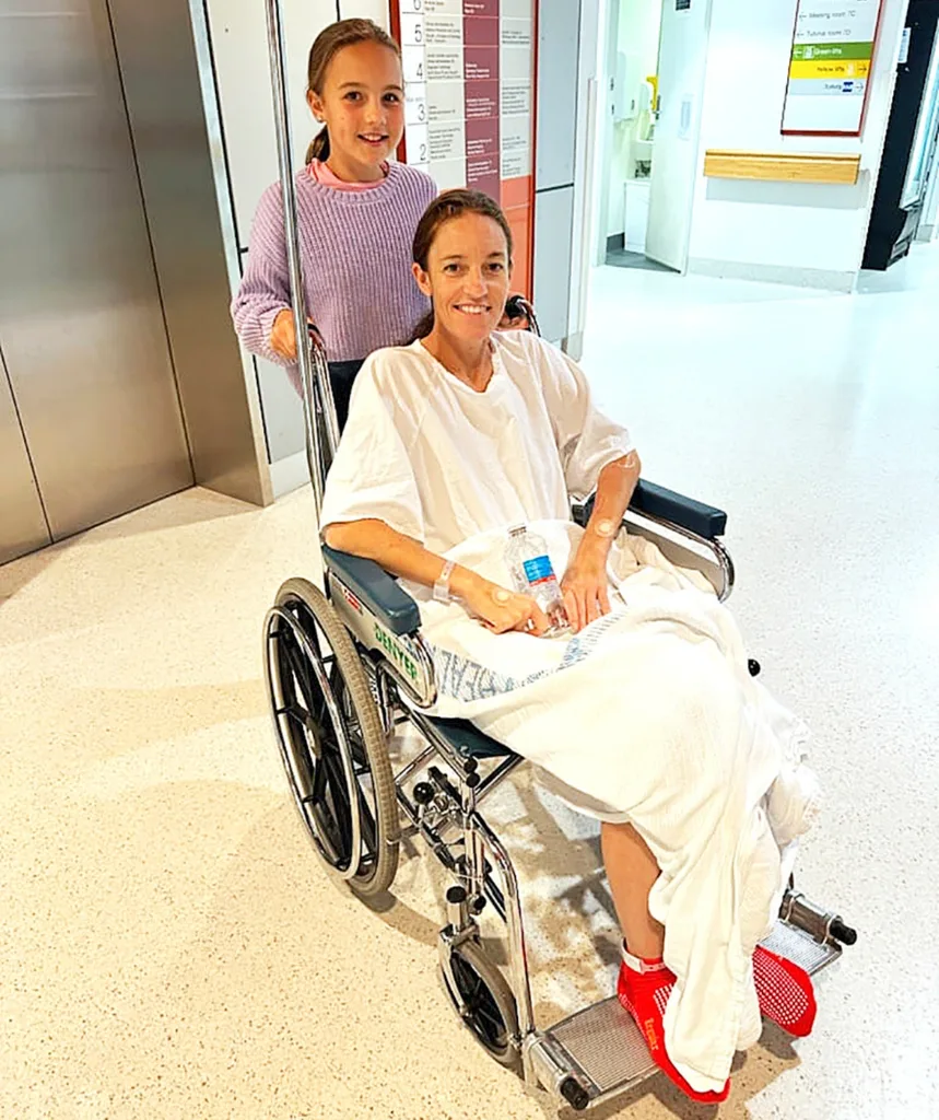 Stacie is pushed in a hospital wheelchair by one of her daughters.