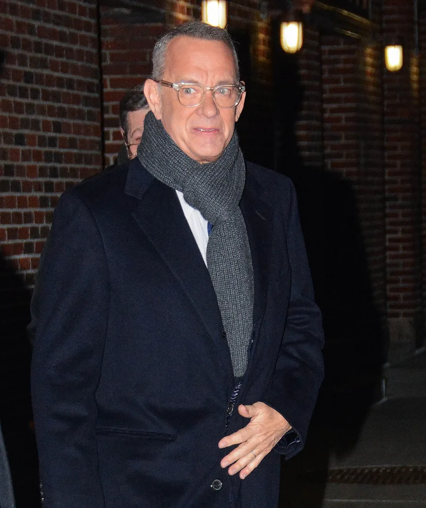 Tom Hanks stands in navy coat and grey scarf