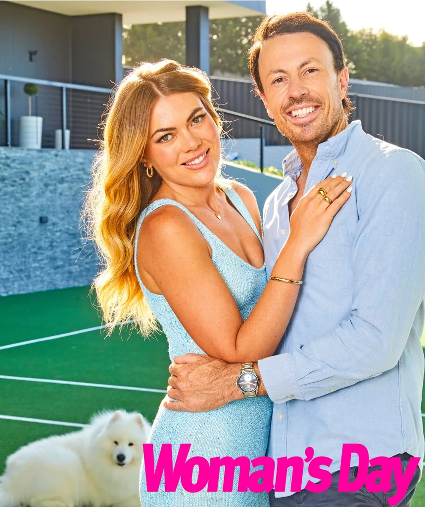 Jacqui and Clint pose on their tennis court with Clint's dog in the background