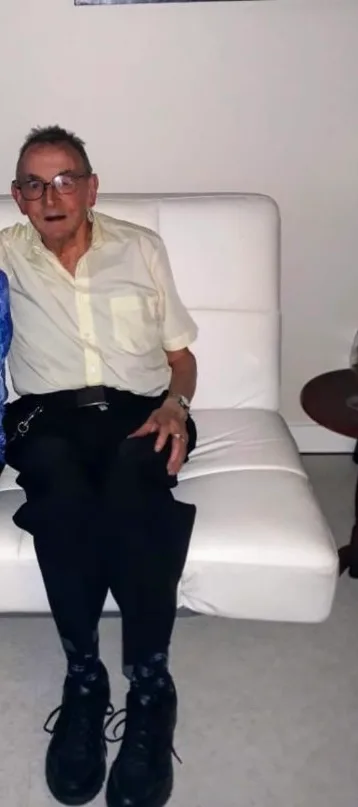 Margaret's elderly neighbour David sitting on a white couch