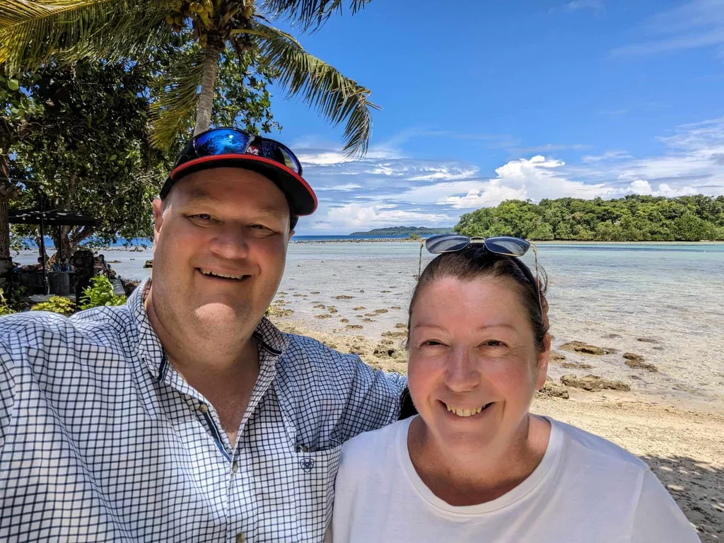 Jeff and Melanie on a beach in front of palm trees