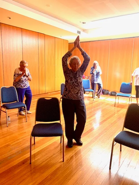 Bonnie at yoga with her hands clasped together above her head