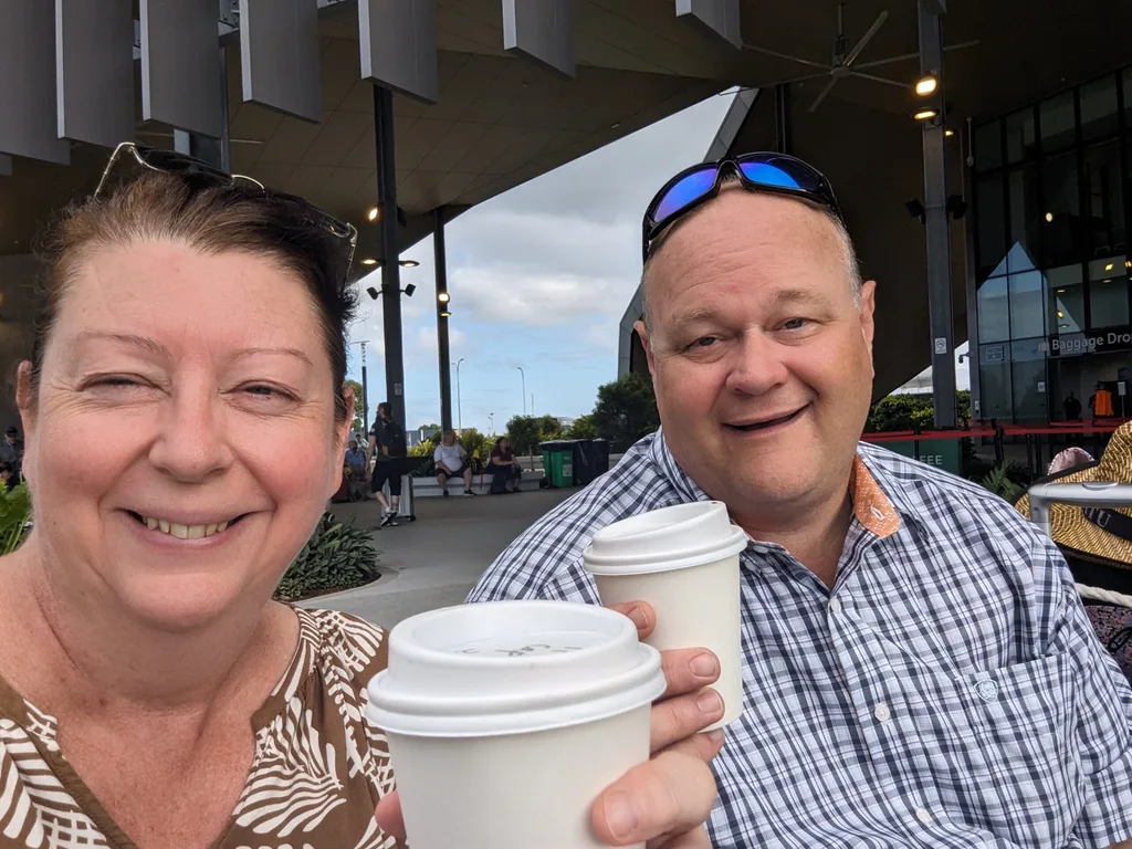 Melanie and Jeff cheersing with takeaway coffee cups