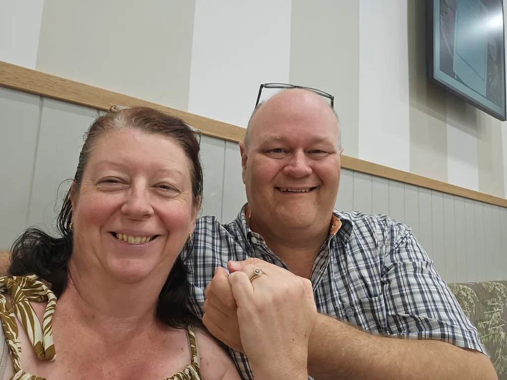 Melanie holding Jeff's hand with her newly adorned hand with the engagement ring