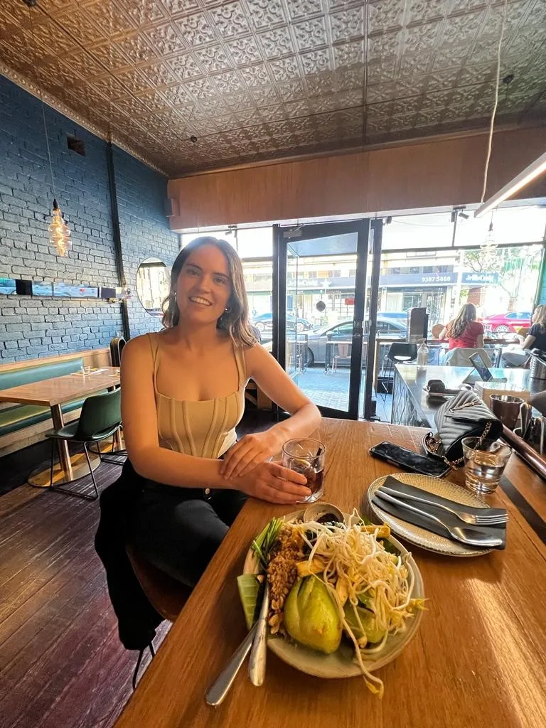 Zoe sitting at a fancy city restaurant sipping a cocktail