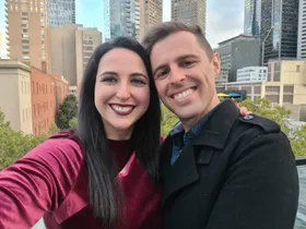 Elinor and Daniel on a rooftop with tall buildings behind them