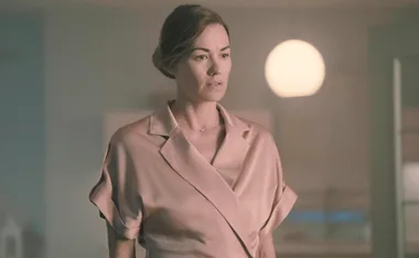 Serena in a beige silk shirt with her blonde hair tied up in a bun and sombre look on her face