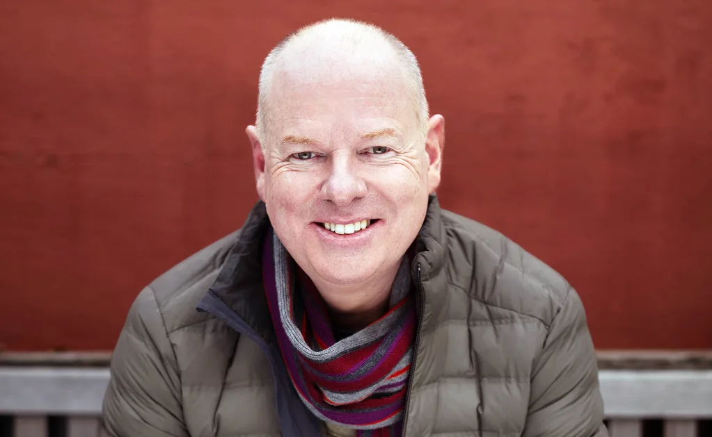 Tom, dressed warmly, smiles at the camera.