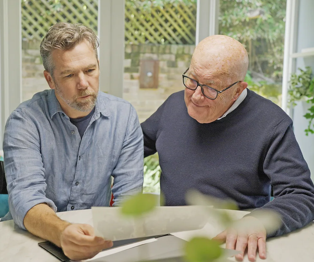 Patrick sits next to his uncle David, and the two of them look over documents together.