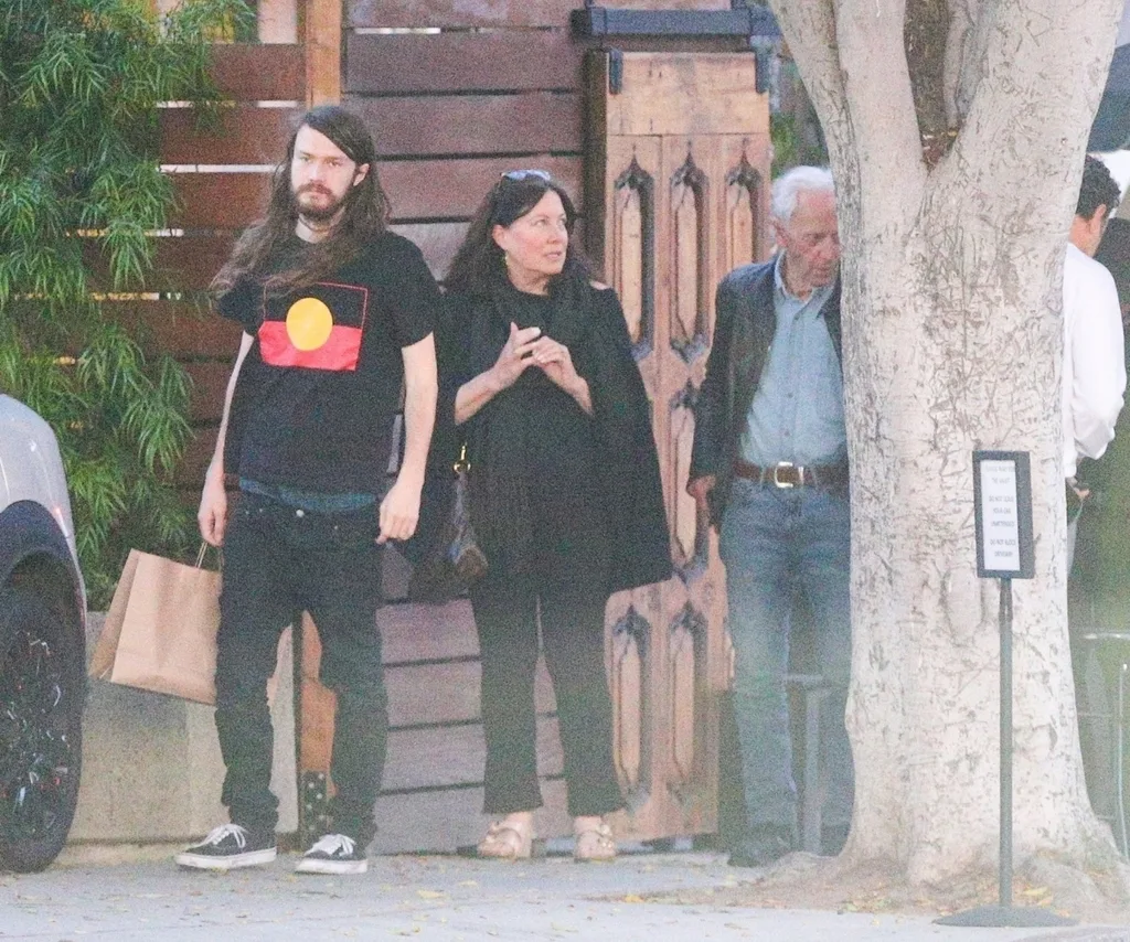 Three people stand on a street corner.
