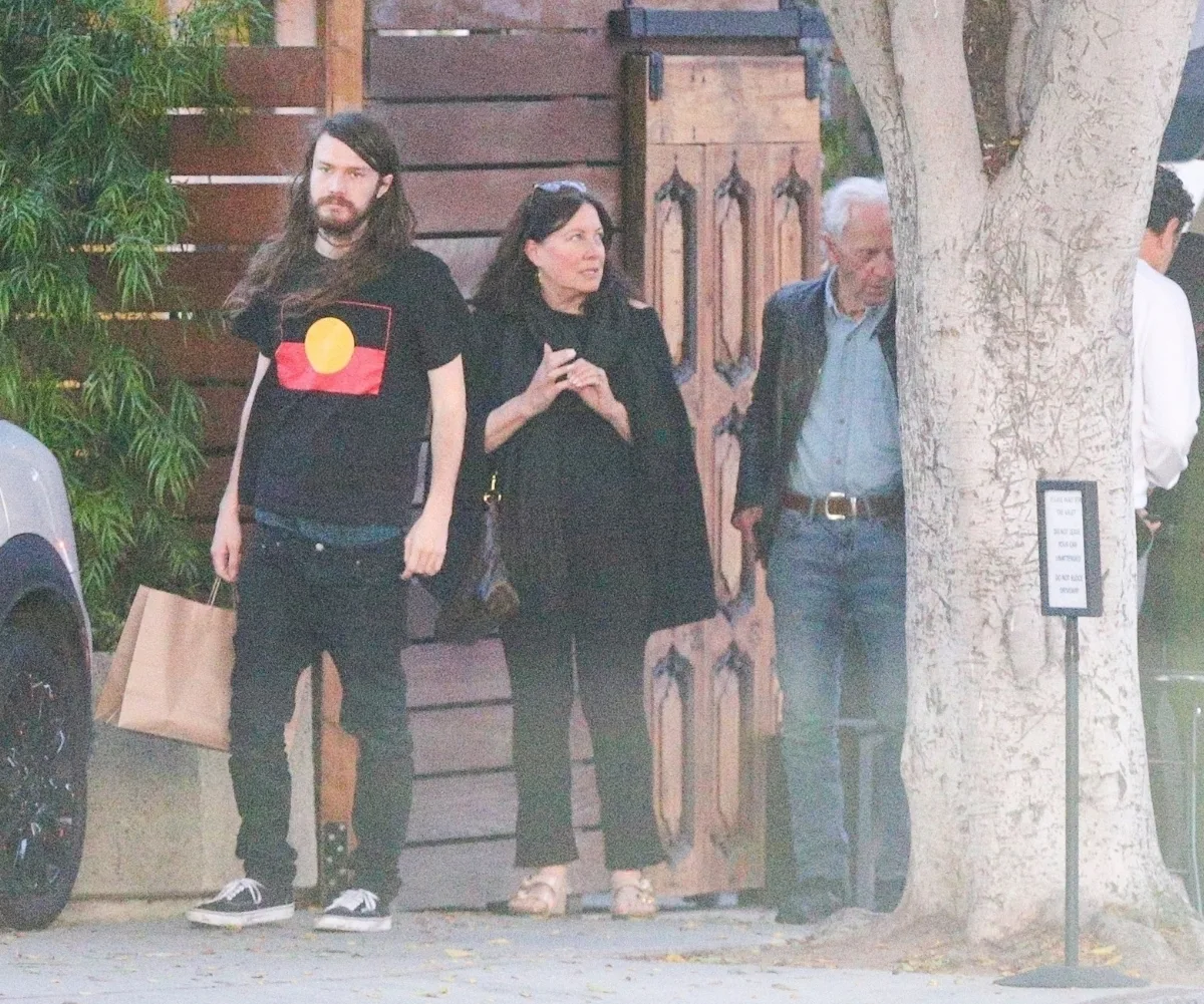 Three people stand on a street corner.