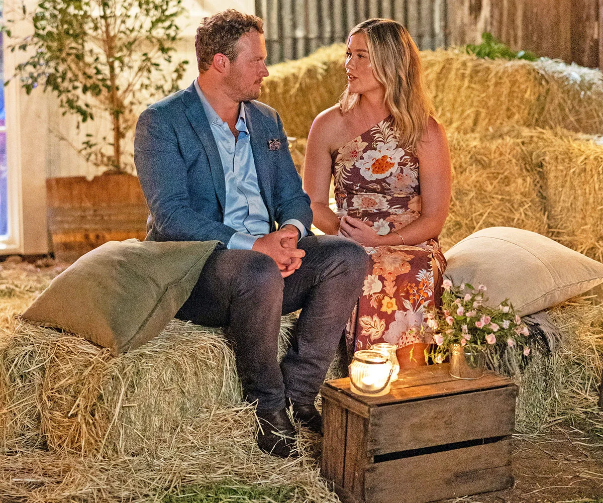 Corey and Chloe look into each other's eyes while sitting on haybales at the country ball. 