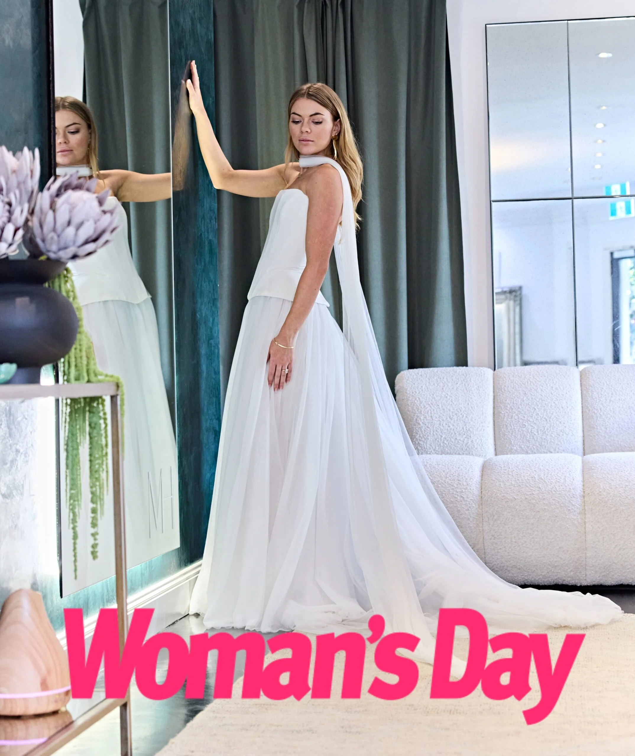 Jacqui poses next to a mirror in a two piece gown with scarf