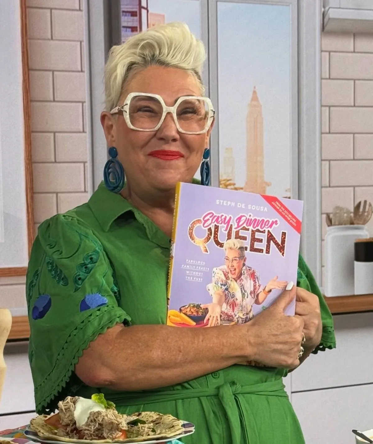 Steph holding up her Easy Dinner Queen cookbook