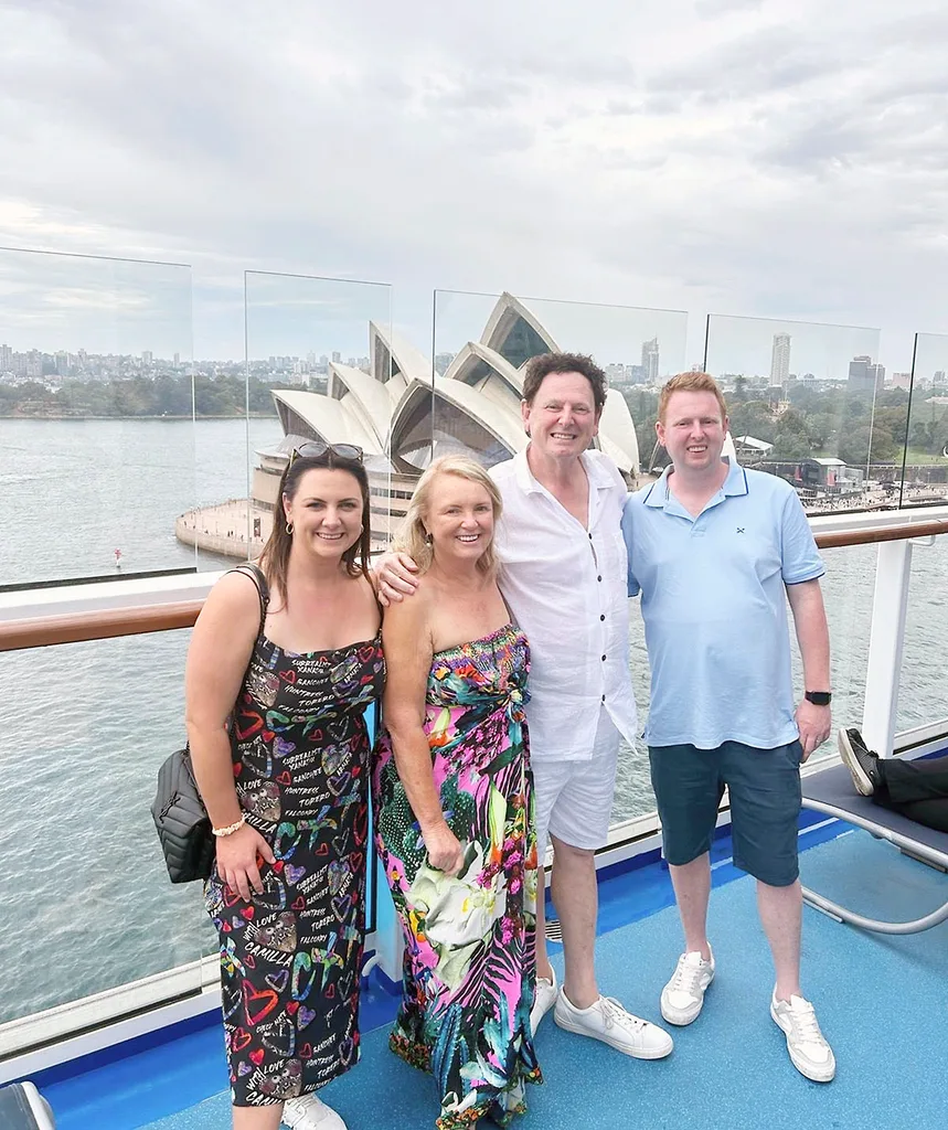 The Fren family pose in front of the Sydney Opera House on a cloudy day.