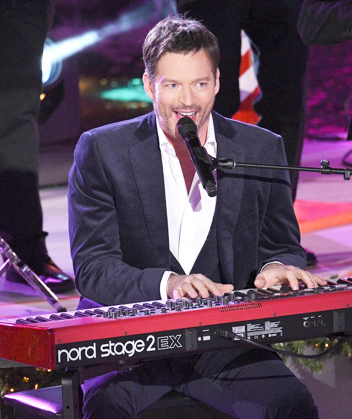 Harry plays a keyboard and sings into a microphone on stage in New York