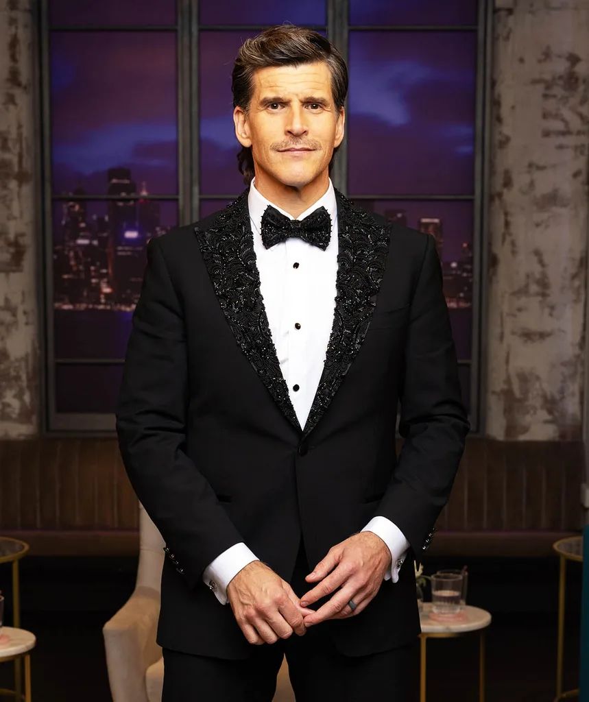 Osher Gunsberg dressed in a black suit and tie as he hosts the Real Housewives of Sydney reunion