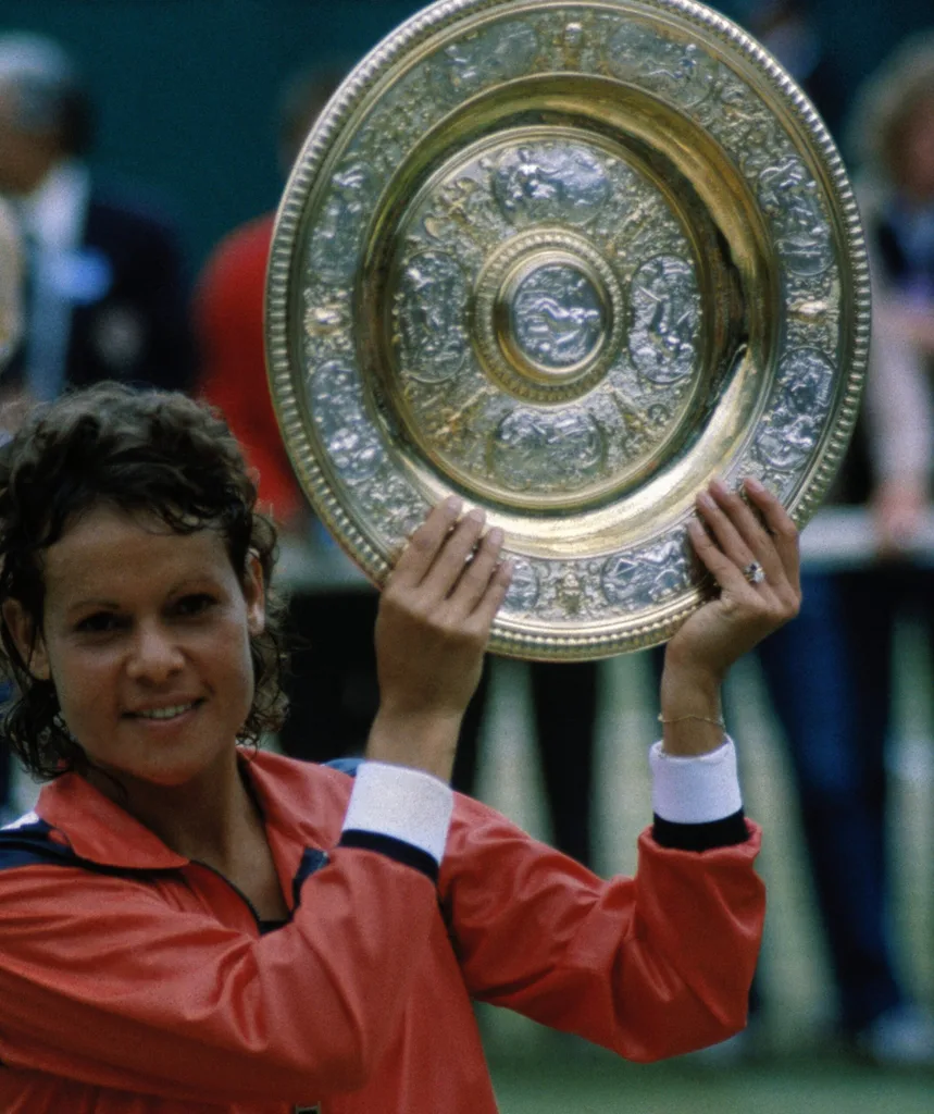 A woman holds up a round medal.