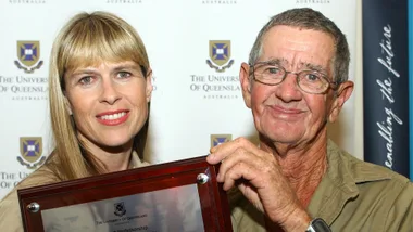 A blonde woman and older man stand together.