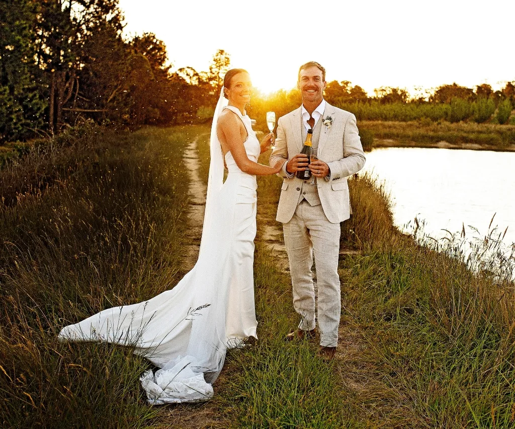 Farmer David and his wife Emily stand along a river with the sunset in the background