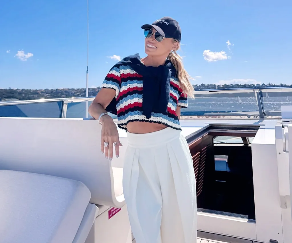 Sonia poses in white trousers and a cap on a yacht.