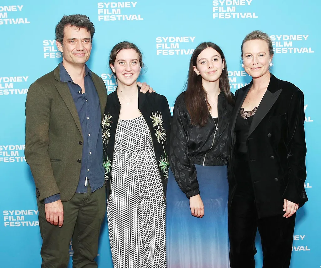 Marta and her husband Ben Winspear and their daughters Grace and Maggie stand in front of a blue background.