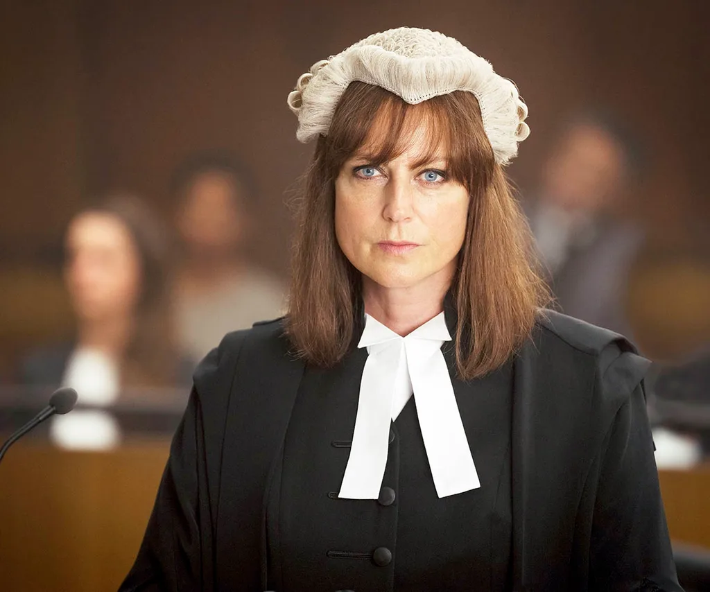 Marta, with brown hair and a fringe, wears a legal wig and gown on the set of The Twelve.