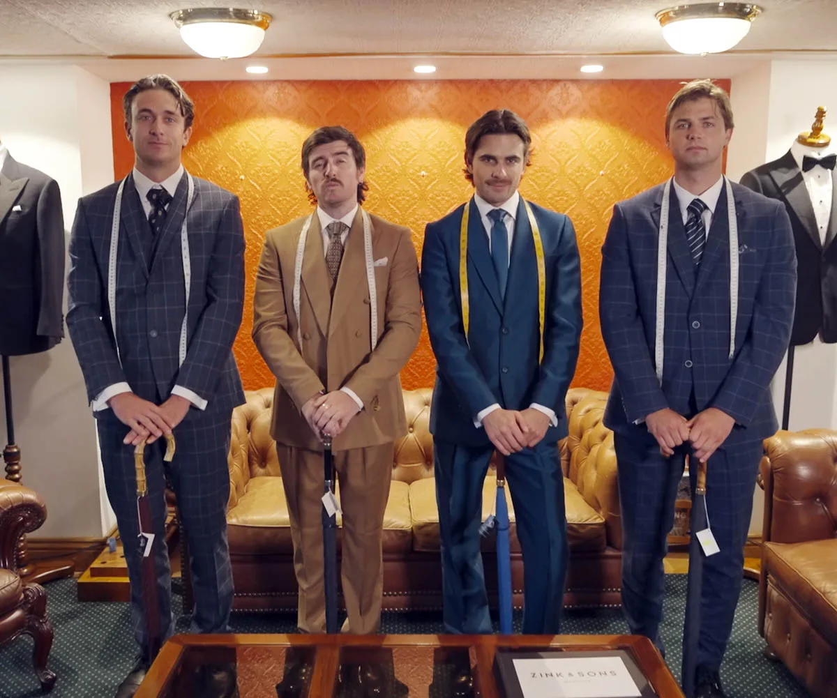 Jack, Dom, Matt and Liam are all suited up in nice suits with tailoring tape around their necks as they pose for the camera with their hands crossed in front of them
