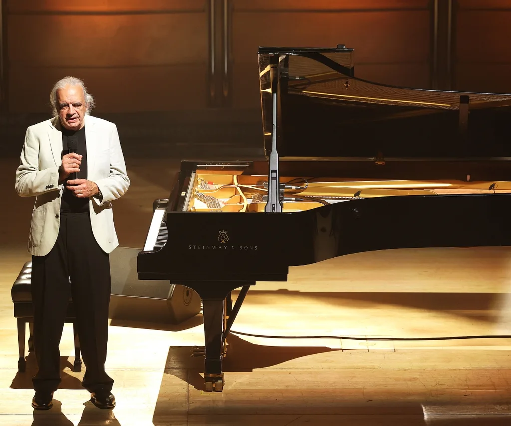 A man stands by a piano.