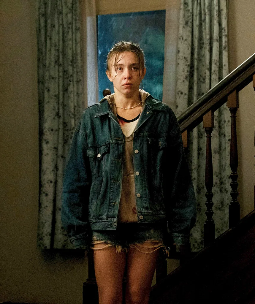 Sydney Sweeney, looking scruffy, stands near the bottom of a staircase in a scene from Echo Valley.