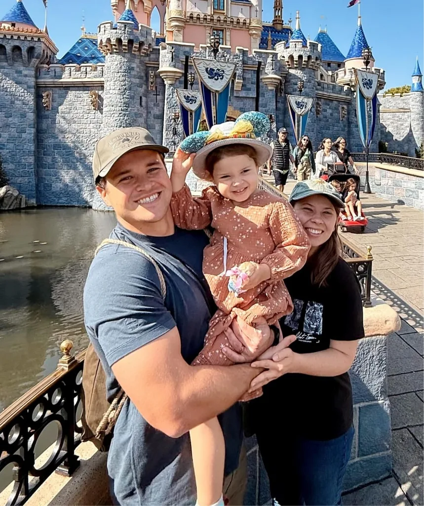 A mum, dad and daughter smile to camera.