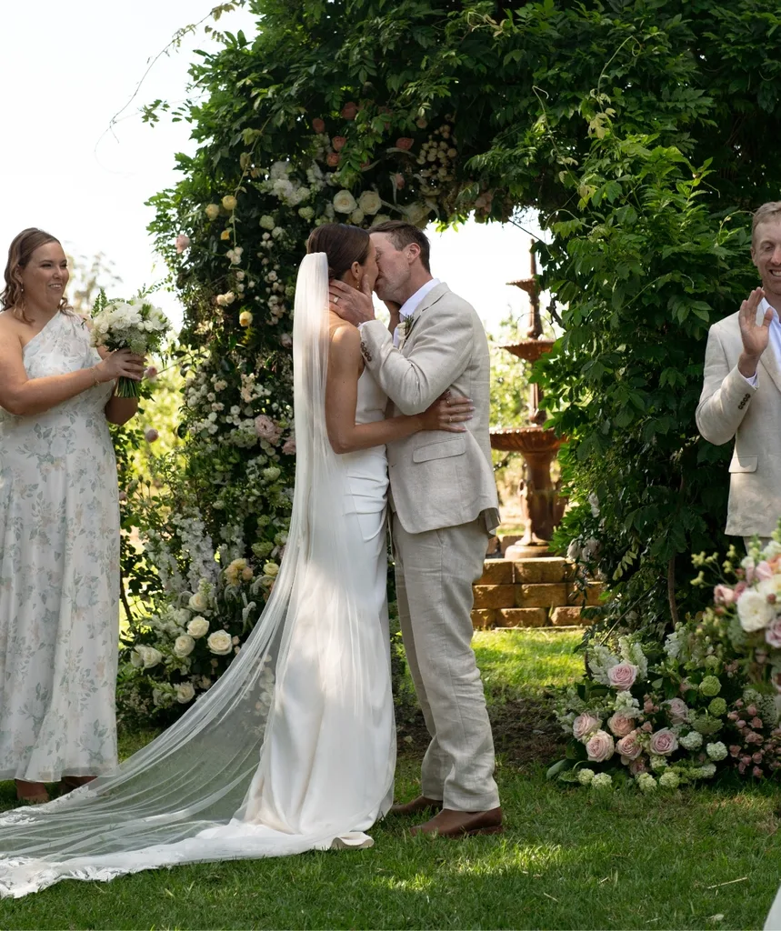 Farmer David and Emily kiss under a green canopy at their wedding